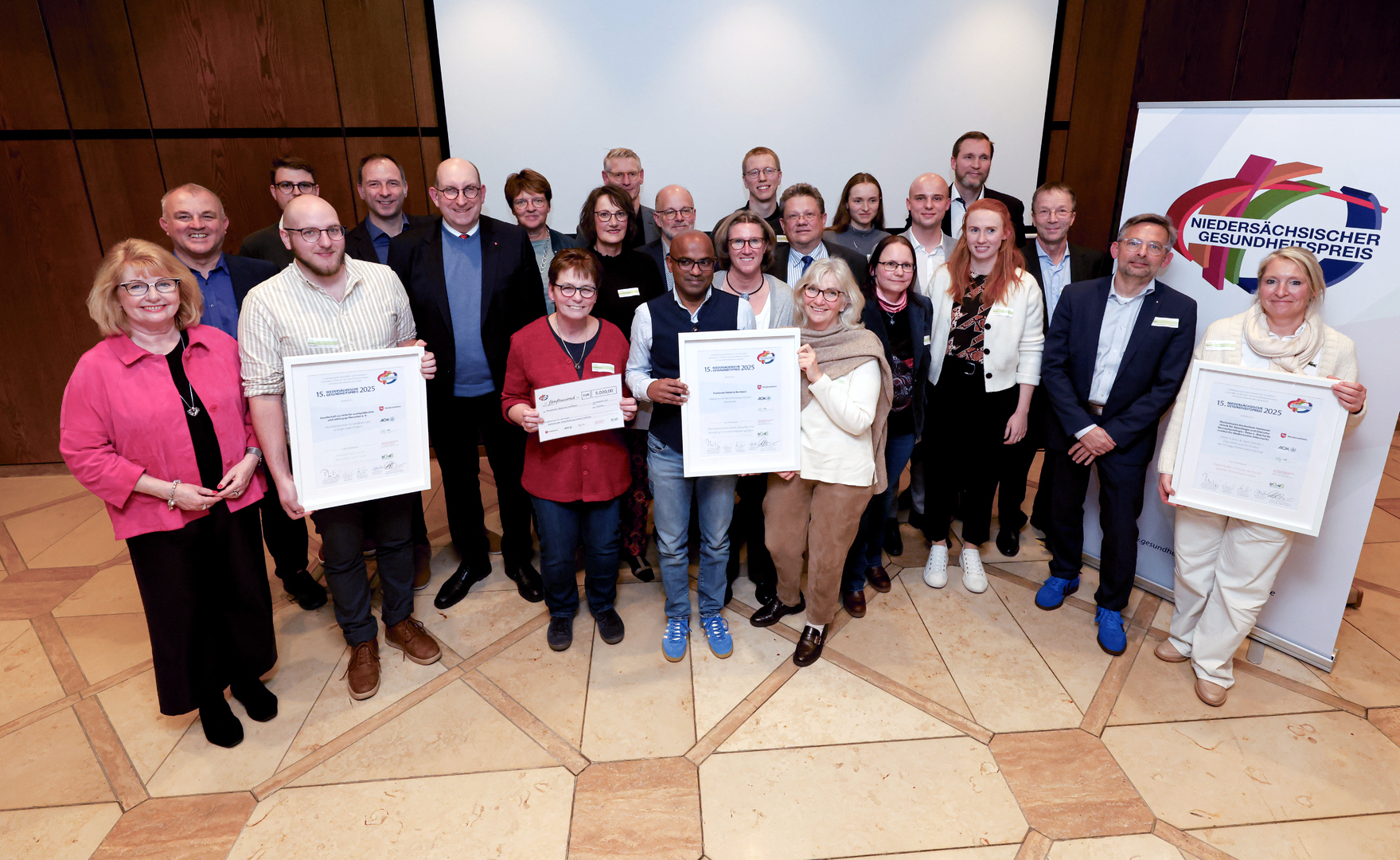 Alle Preisträger des Gesundheitspreises 2025 halten Ihre Urkunden in einem Gruppenfoto hoch.